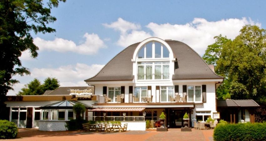 Waldgasthof Schöning Haupthaus. Weißes Haus mit Terrasse. Rechts ein Wintergarten, links eine Restauranterweiterung mit Flachdach.