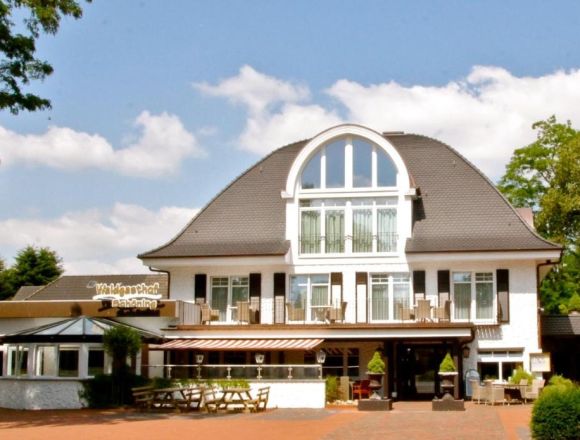 Waldgasthof Schöning Haupthaus. Weißes Haus mit Terrasse. Rechts ein Wintergarten, links eine Restauranterweiterung mit Flachdach.