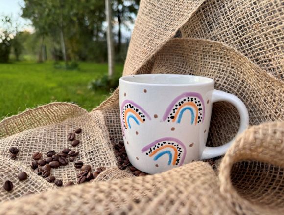 bemalte Keramiktasse auf einem Kaffeesack mit Kaffeebohnen